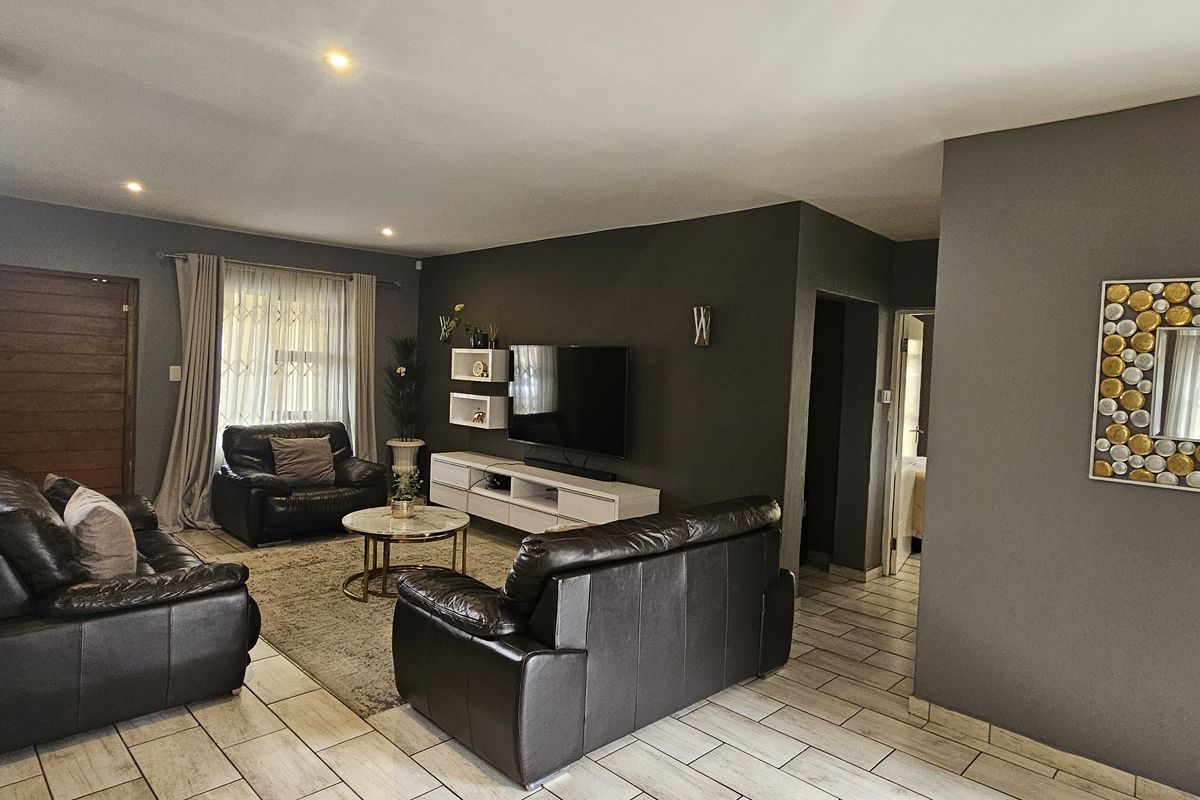 A well-maintained living room featuring tiled flooring, recessed downlights, and a distinctive stone feature wall, creating a modern and comfortable atmosphere.