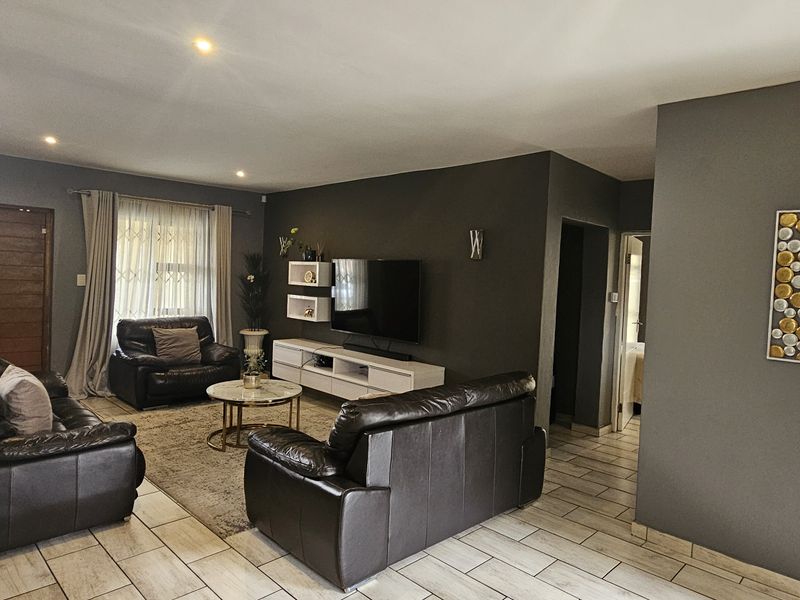 A well-maintained living room featuring tiled flooring, recessed downlights, and a distinctive stone feature wall, creating a modern and comfortable atmosphere.