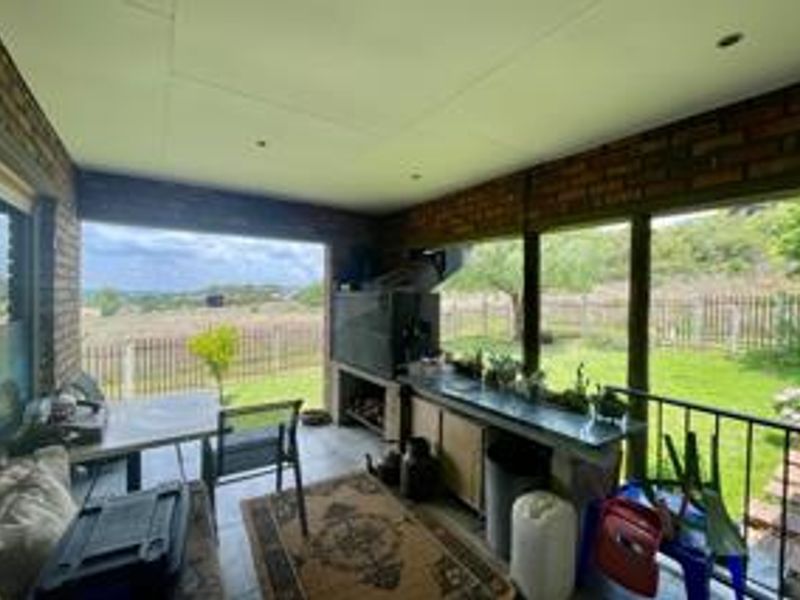 Covered patio area featuring a built-in braai, brick wall finishes, and direct access to the garden with scenic views.