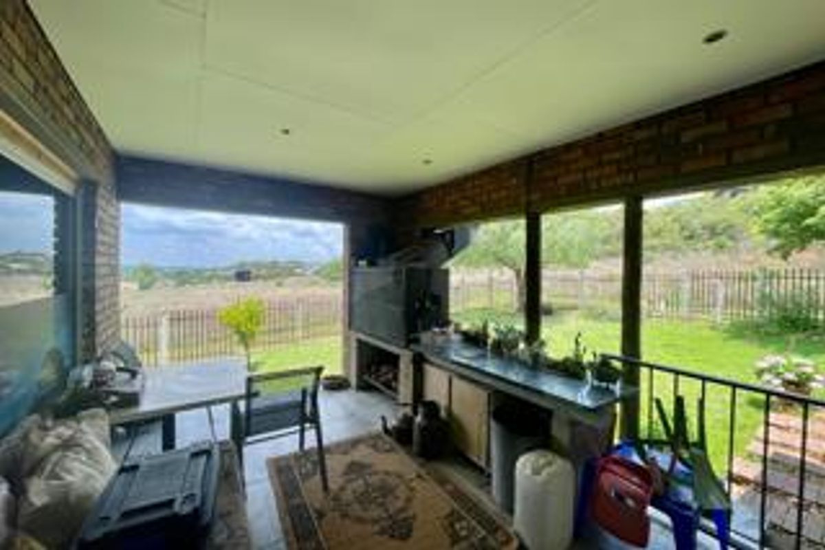 Covered patio area featuring a built-in braai, brick wall finishes, and direct access to the garden with scenic views.