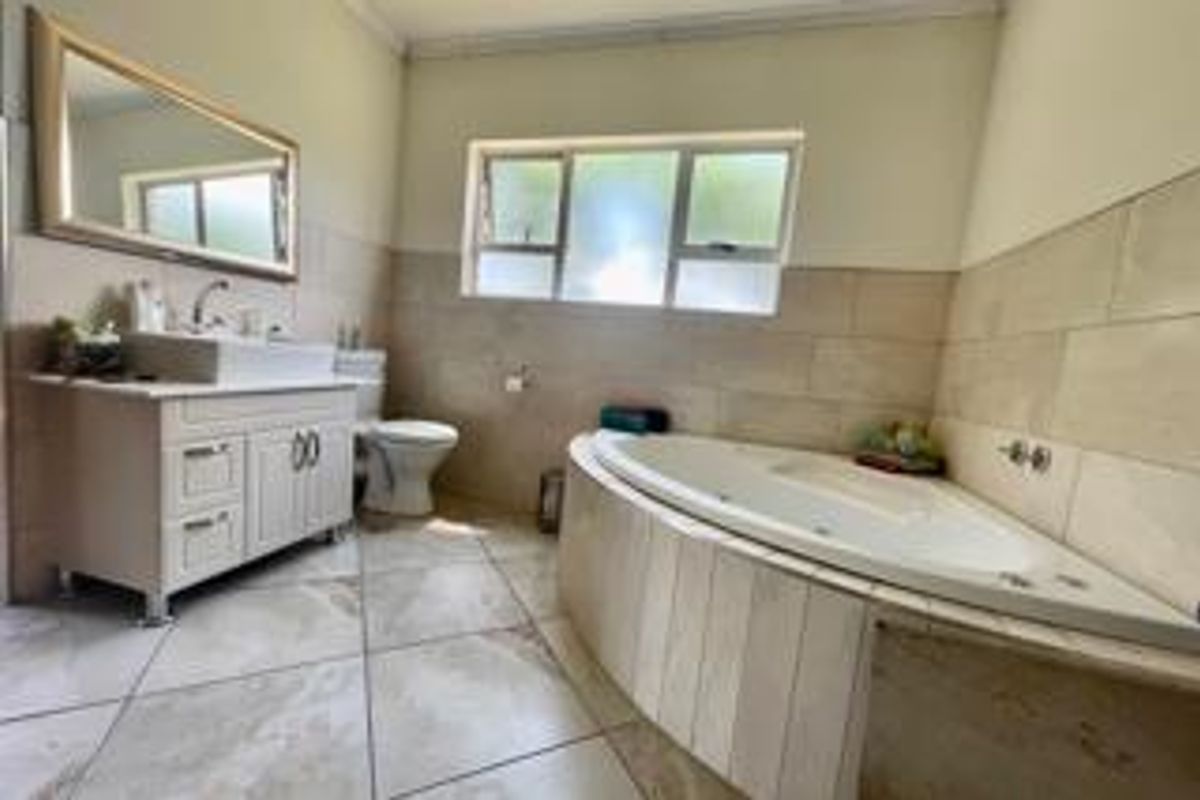 A well-maintained bathroom featuring a corner bathtub, a modern vanity with a vessel sink, and neutral wall and floor tiling.
