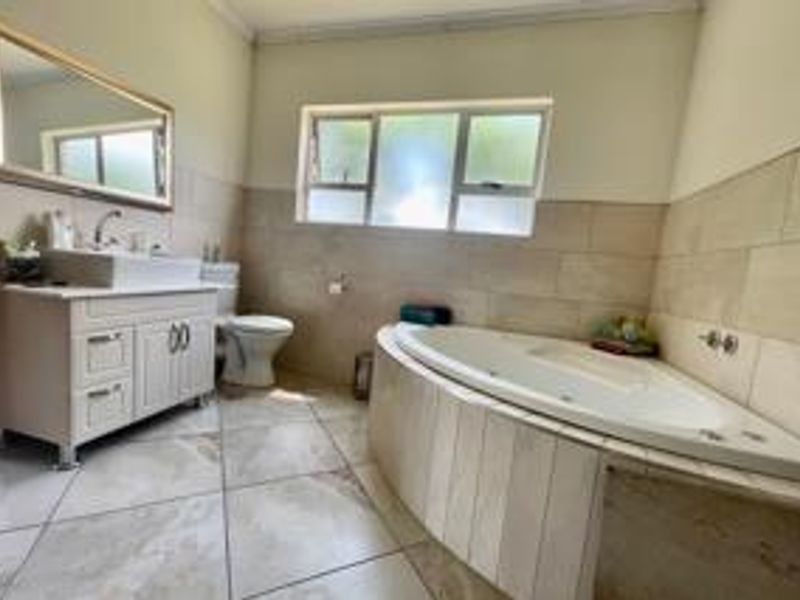 A well-maintained bathroom featuring a corner bathtub, a modern vanity with a vessel sink, and neutral wall and floor tiling.