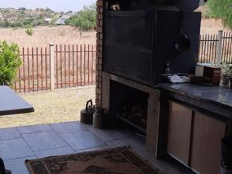 Covered patio area featuring a built-in braai, tiled flooring, and direct access to the rear garden with scenic views.