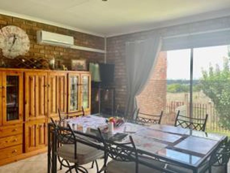 Dining room featuring exposed brick walls, a wall-mounted air conditioning unit, and large sliding glass doors providing natural light and outdoor access.