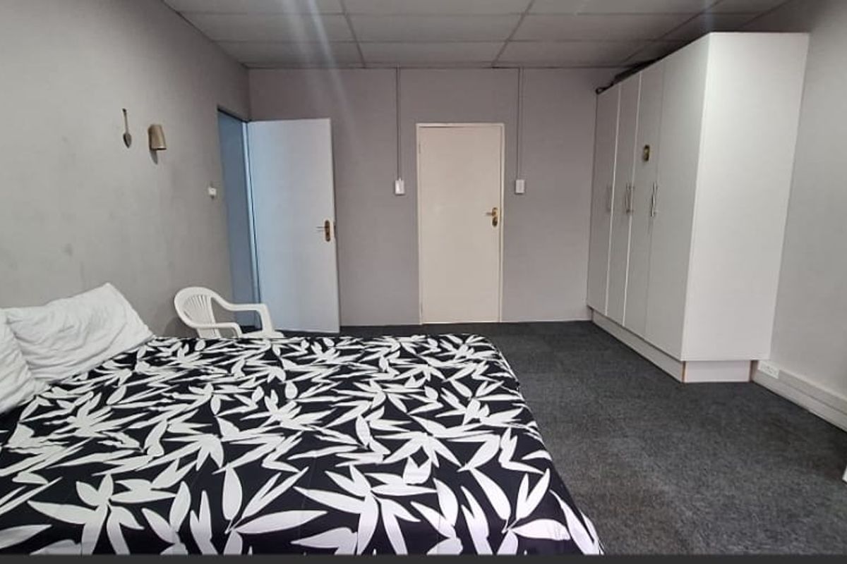 A spacious bedroom featuring built-in wardrobes, carpeted flooring, and surface-mounted electrical fixtures, offering a functional layout ready for cosmetic updates.