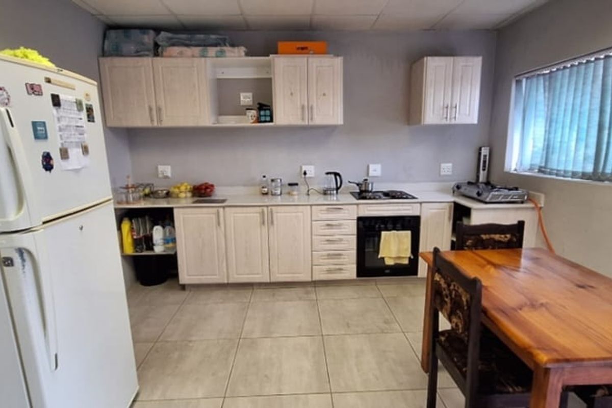 A functional kitchen featuring light-toned cabinetry, built-in oven, hob, and tiled flooring, offering a practical layout for daily meal preparation.