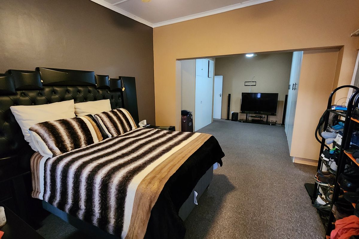 Spacious bedroom featuring carpeted flooring and integrated built-in cupboards, offering a functional layout with an adjoining dressing or lounge area.