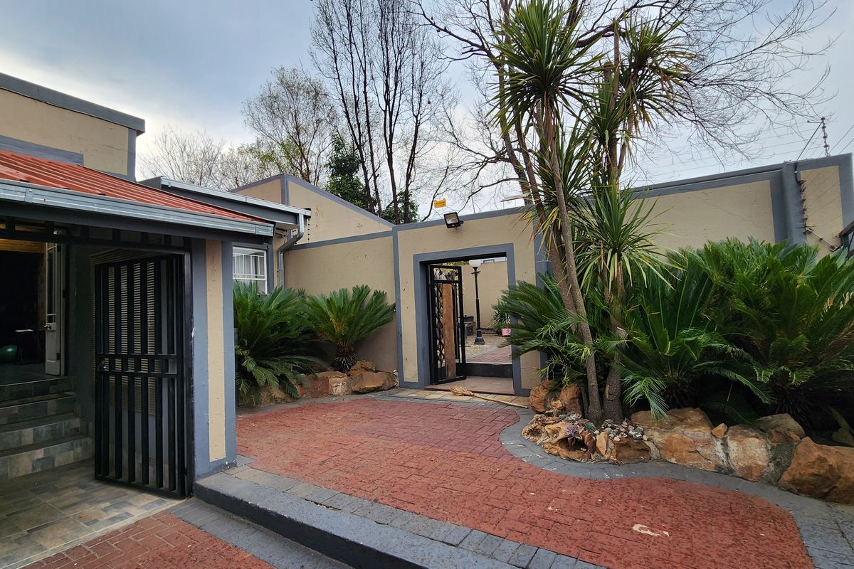 A private rear courtyard featuring paved flooring, established garden beds with rockery, and secure gated access to the property.