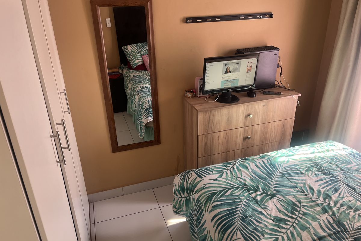 A bedroom featuring tiled flooring and a built-in wardrobe, providing functional storage space within the room.