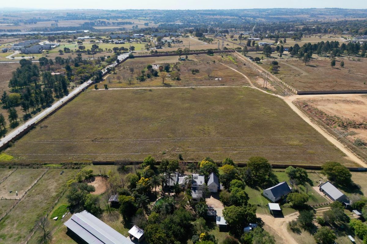 Aerial view of a large residential vacant land plot featuring established perimeter fencing, mature trees, and proximity to existing residential infrastructure.