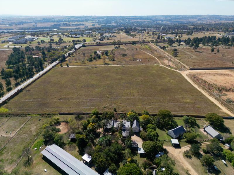 Aerial view of a large residential vacant land plot featuring established perimeter fencing, mature trees, and proximity to existing residential infrastructure.