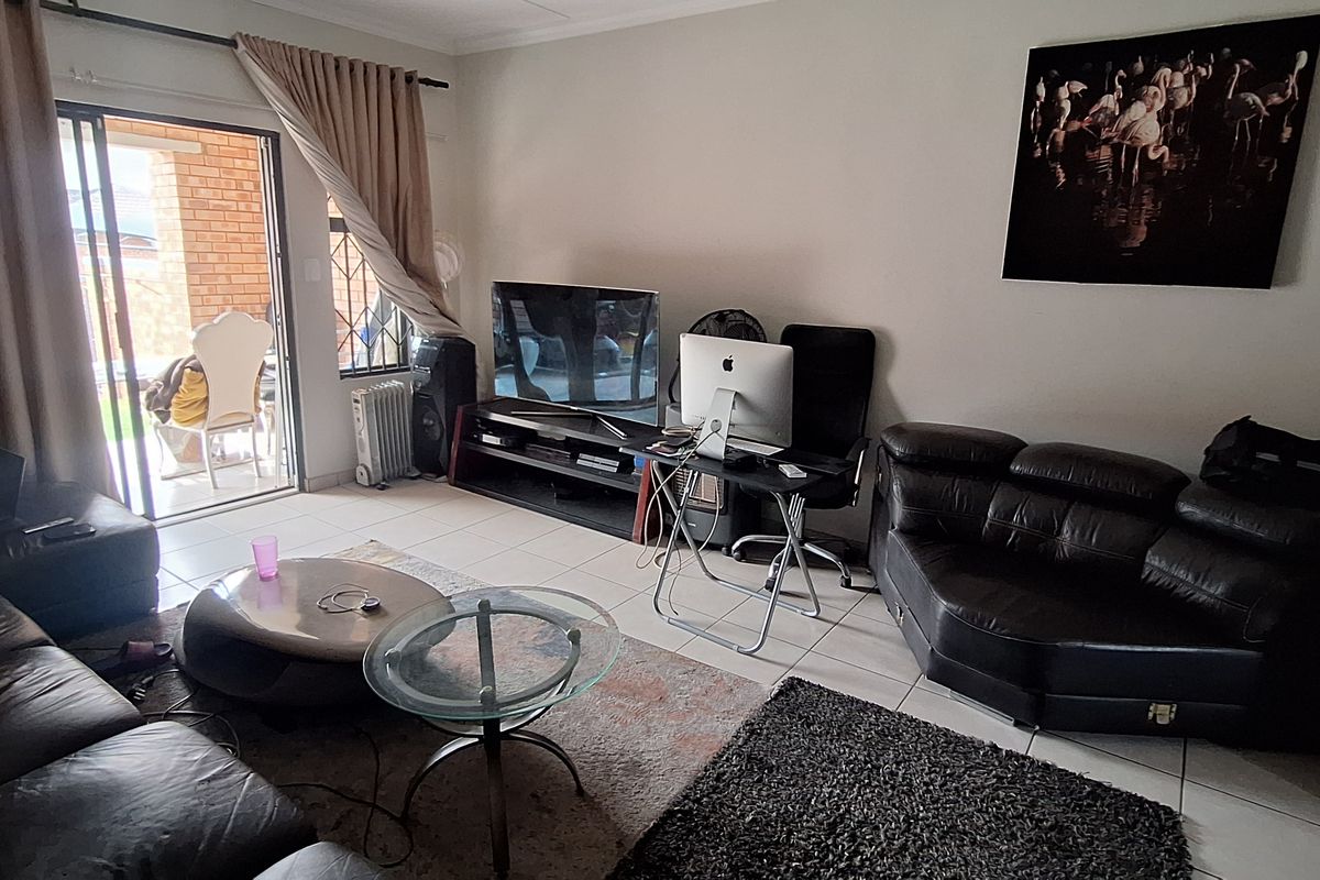 A living room featuring tiled flooring and a sliding glass door providing access to an outdoor area.