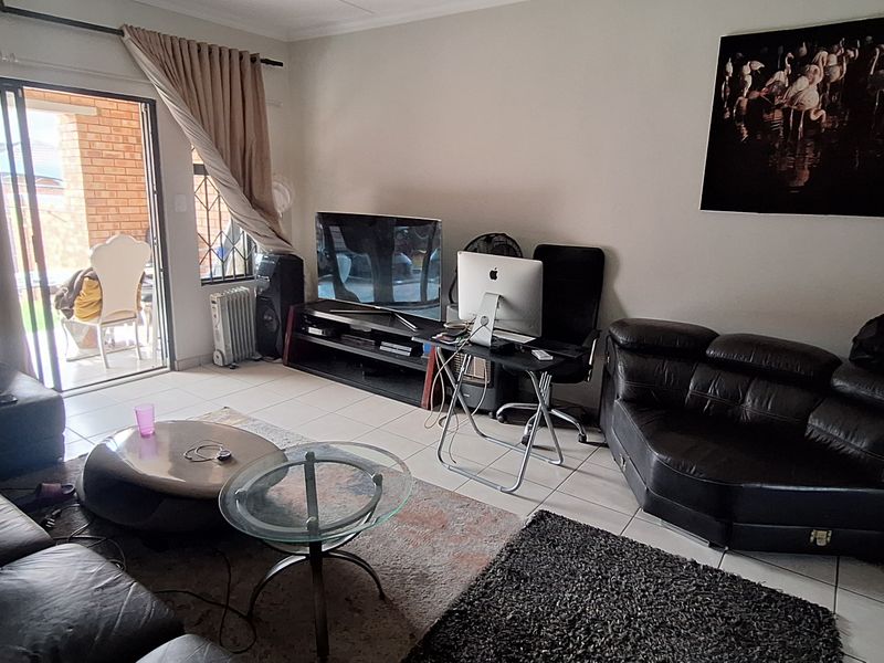 A living room featuring tiled flooring and a sliding glass door providing access to an outdoor area.