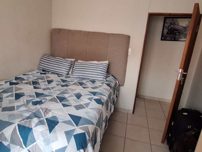 A compact bedroom featuring tiled flooring and a standard internal door, providing a functional living space.