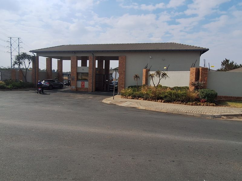 The main entrance and security gatehouse of the Franklin 8 apartment complex, featuring brick masonry, electric fencing, and a paved access point.