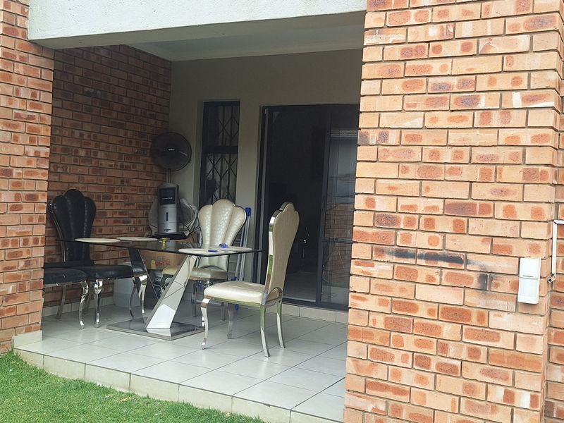 A covered patio area featuring exposed brick walls and tiled flooring, providing direct access to the interior through a sliding glass door.