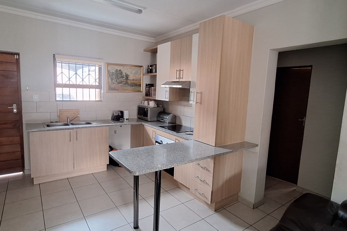 Functional kitchen featuring laminate cabinetry, granite countertops, a breakfast bar, and integrated appliances, finished with ceramic tile flooring.