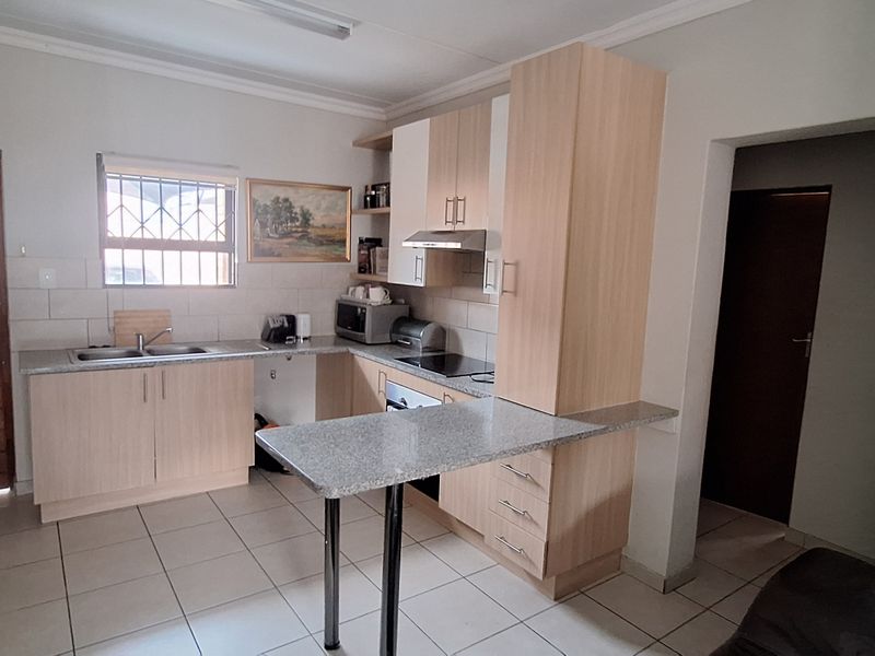 Functional kitchen featuring laminate cabinetry, granite countertops, a breakfast bar, and integrated appliances, finished with ceramic tile flooring.