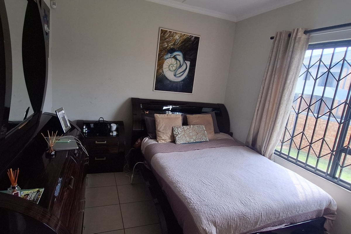 A functional bedroom featuring tiled flooring and a window fitted with a security gate, providing a secure and practical living space.