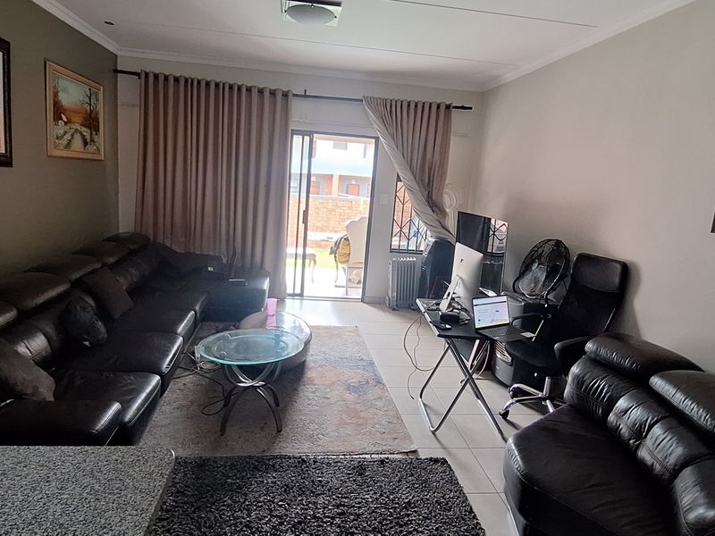A spacious living room featuring tiled flooring and a sliding glass door that provides access to the outdoor area.