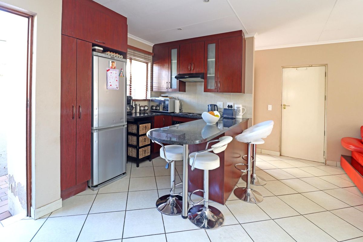 A functional kitchen featuring dark wood cabinetry, granite countertops, a breakfast bar, and tiled flooring with direct access to an outdoor area.