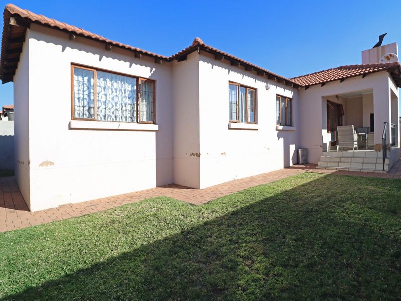 Rear view of the townhouse featuring a paved patio area, small garden, and traditional tiled roof architecture.