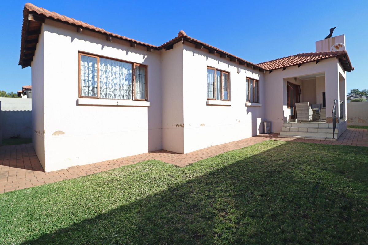 Rear view of the townhouse featuring a paved patio area, small garden, and traditional tiled roof architecture.