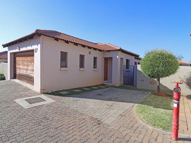 Exterior view of a townhouse featuring a paved driveway, single garage, and a small front garden area.