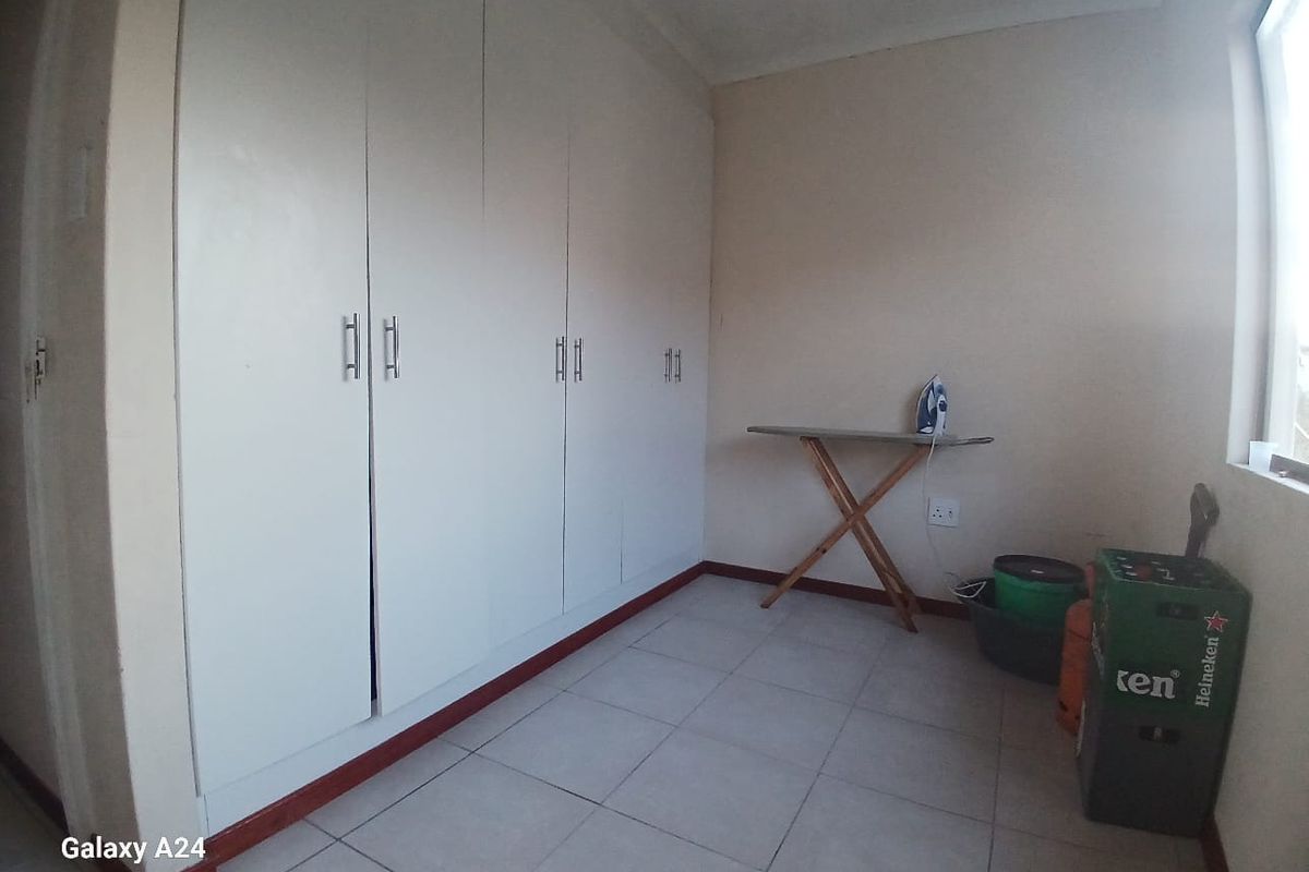 A bedroom featuring neutral tiled flooring and extensive built-in cupboard storage space.