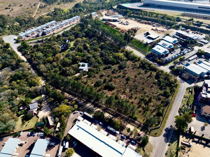 Aerial view of a large, undeveloped residential land parcel featuring mature trees and natural vegetation, situated in a developed suburban area.