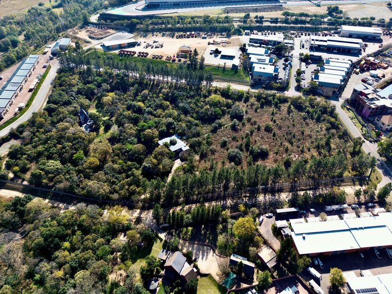 Aerial view of a large, densely wooded residential plot situated in a semi-industrial and commercial area.