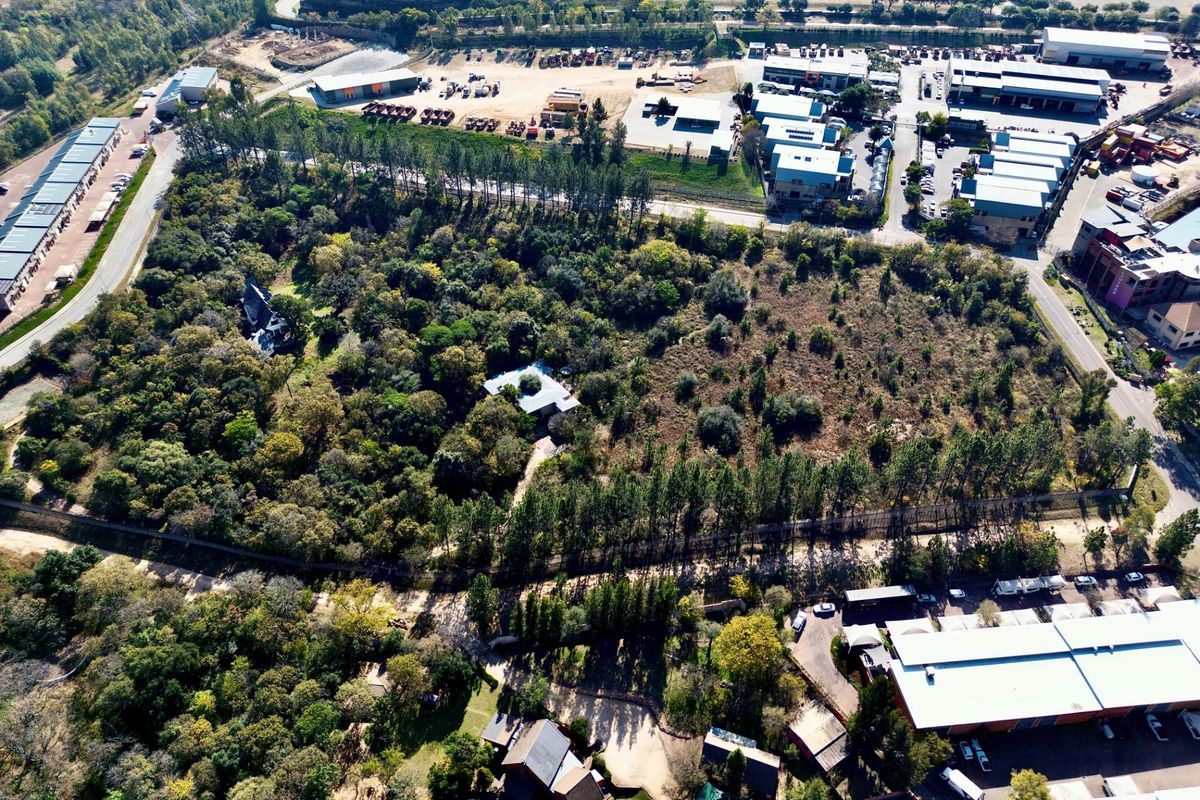 Aerial view of a large, densely wooded residential plot situated in a semi-industrial and commercial area.