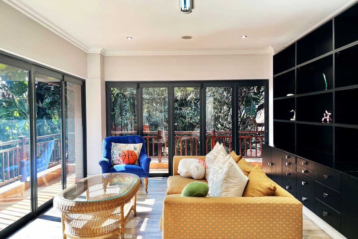 A bright living room featuring large glass sliding doors, built-in black cabinetry, and recessed ceiling lighting, offering a seamless connection to the outdoor balcony.