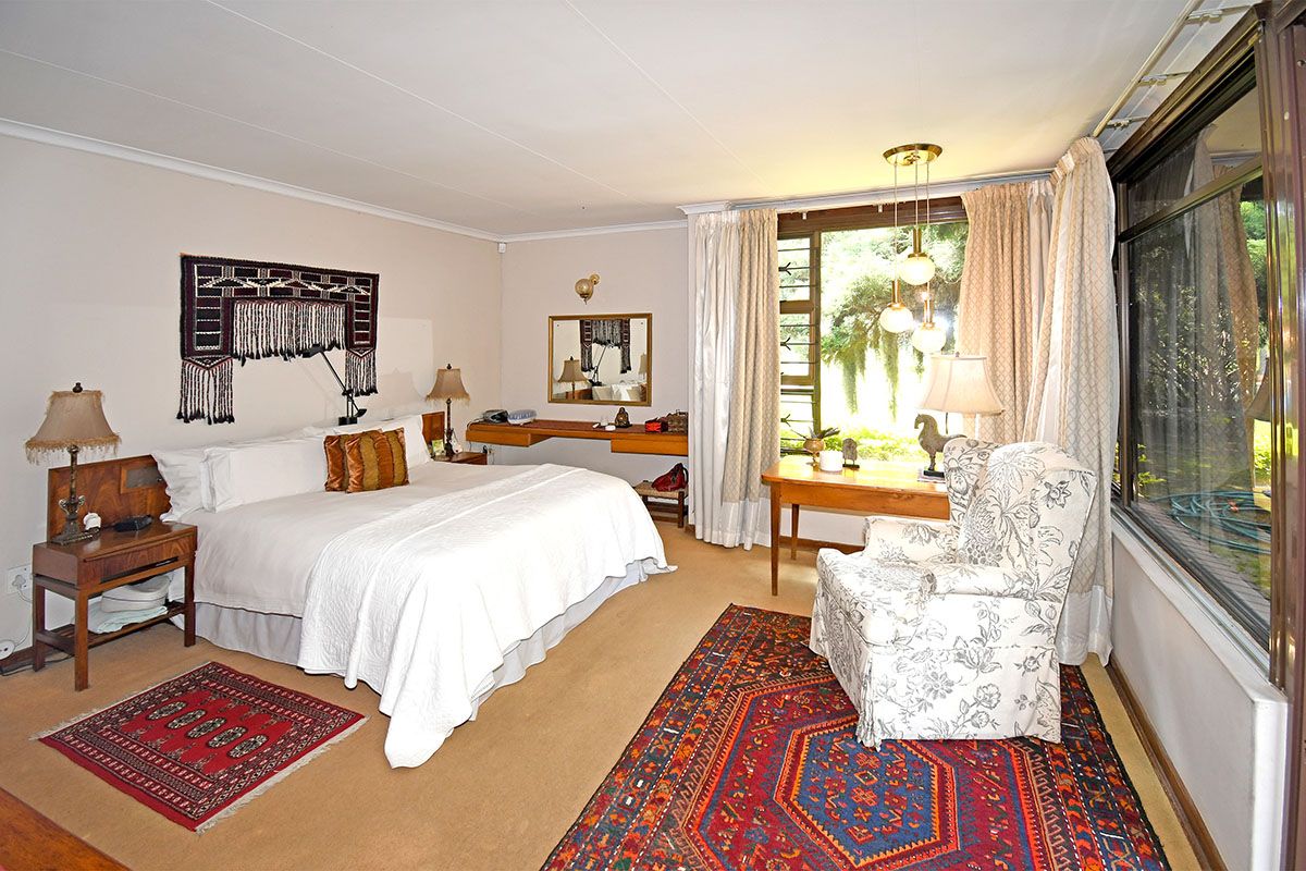 Spacious bedroom featuring large windows, carpeted flooring, and a built-in desk area, offering a comfortable and functional living space.