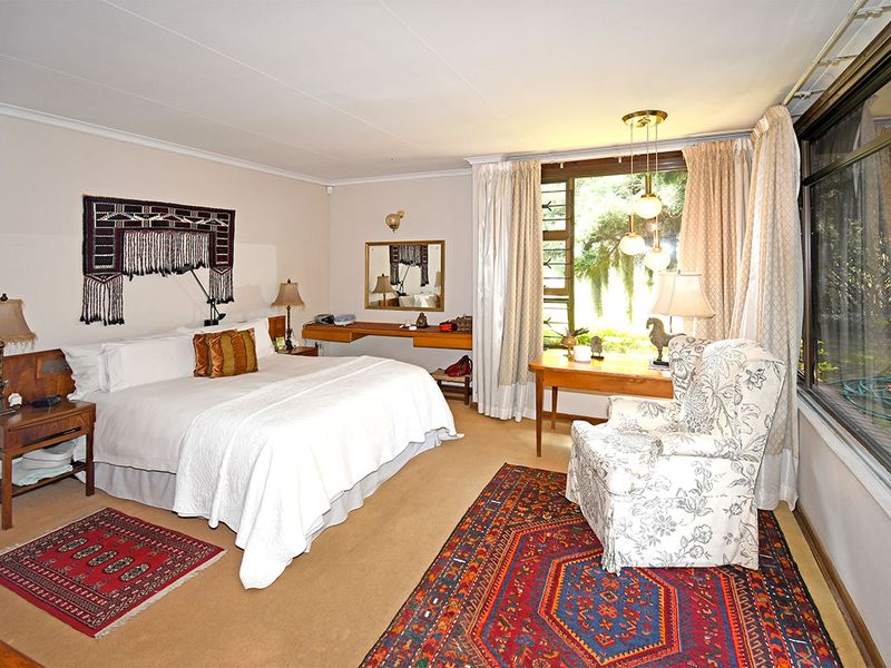 Spacious bedroom featuring large windows, carpeted flooring, and a built-in desk area, offering a comfortable and functional living space.