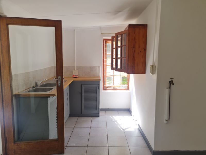 A compact, empty kitchen featuring a double sink, laminate countertops, louvered cabinetry, and tiled flooring, offering a functional space ready for modernization.