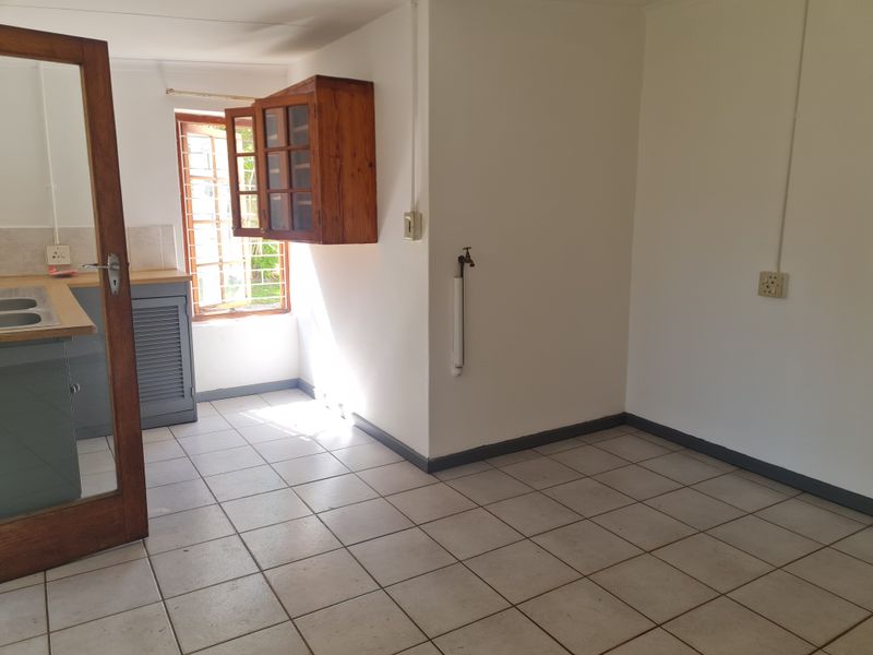 An empty kitchen area featuring tiled flooring, built-in cabinetry, and a wall-mounted tap, offering a blank canvas for renovation.