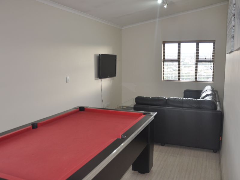 A living room featuring laminate flooring, cove cornicing, and a window with fitted blinds, currently utilized as a recreational space.