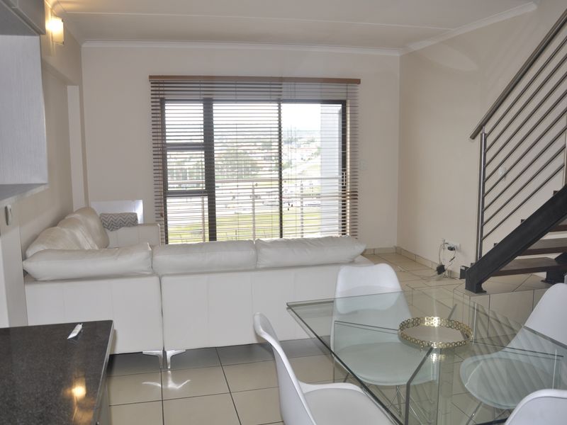 Open plan living and dining area featuring tiled floors, a modern staircase with stainless steel balustrades, and large sliding doors with venetian blinds.