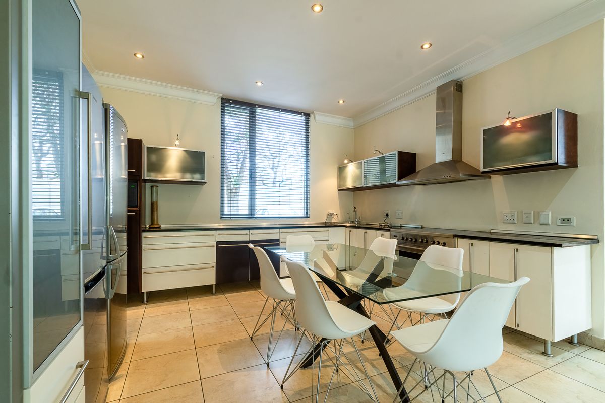 Modern kitchen featuring sleek cabinetry, stainless steel appliances, stone countertops, and tiled flooring, offering a functional and well-lit culinary space.