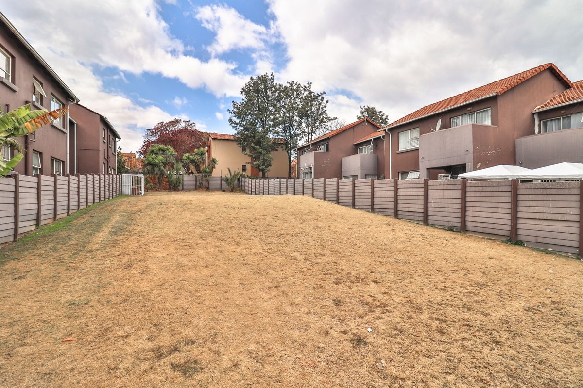A spacious, open rear garden area enclosed by precast concrete boundary walls, featuring views of the surrounding apartment complex buildings.