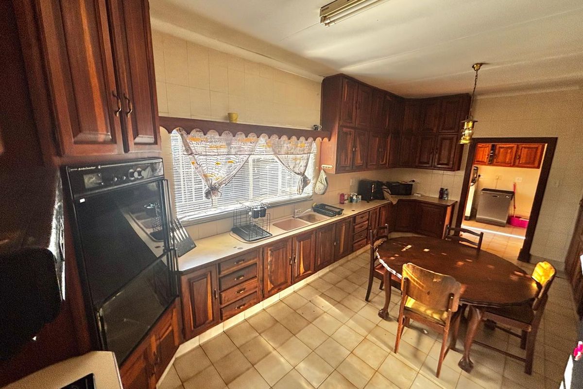 Spacious kitchen featuring traditional timber cabinetry, built-in wall oven, double sink, and tiled flooring, with an adjacent scullery area.