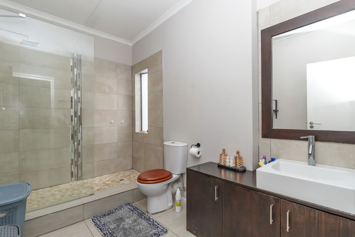 Modern bathroom featuring a walk-in glass shower with tiled walls, a vanity with a vessel sink, and a toilet.