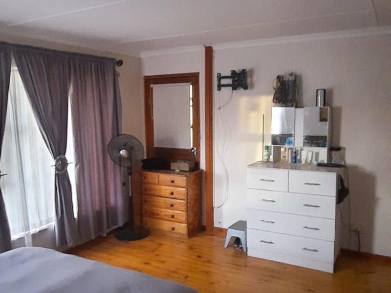 A bedroom featuring polished timber flooring, a ceiling-mounted light fixture, and a wall-mounted television bracket.