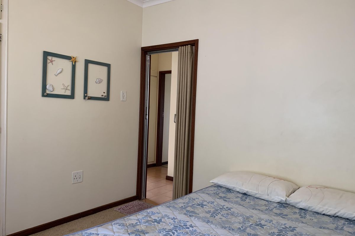 A bedroom featuring neutral walls, carpeted flooring, and a folding door leading to an adjacent hallway.