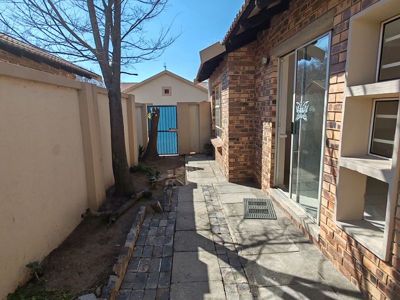 Rear exterior view of the property featuring a face brick facade, paved walkway, and a sliding glass door leading into the home.