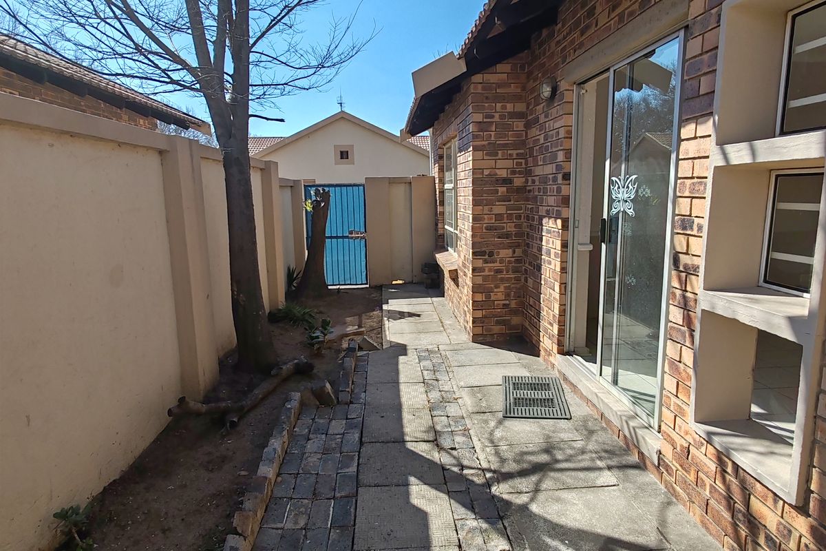 Rear exterior view of the property featuring a face brick facade, paved walkway, and a sliding glass door leading into the home.