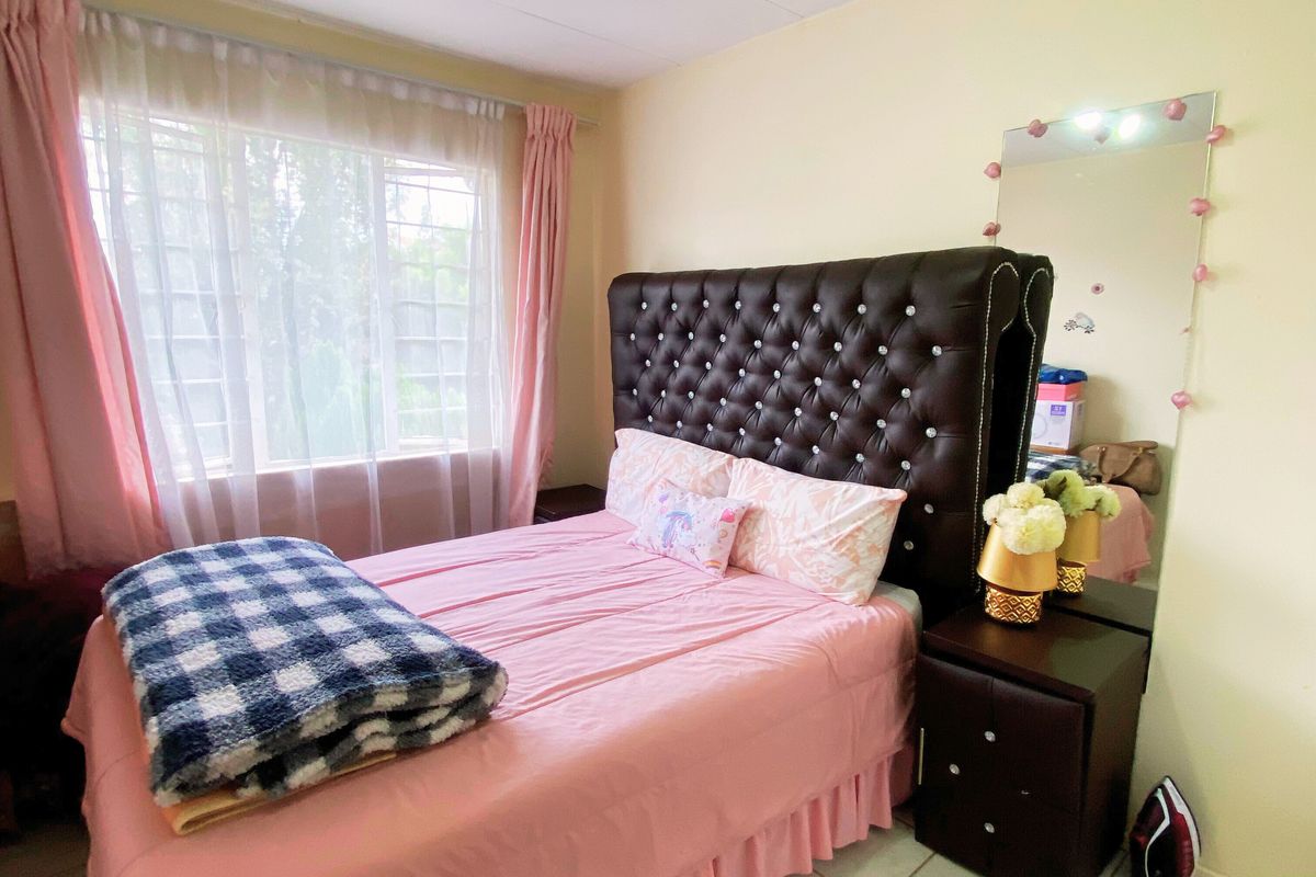 A bedroom featuring tiled flooring, a large window with natural light, and a ceiling-mounted spotlight fixture.