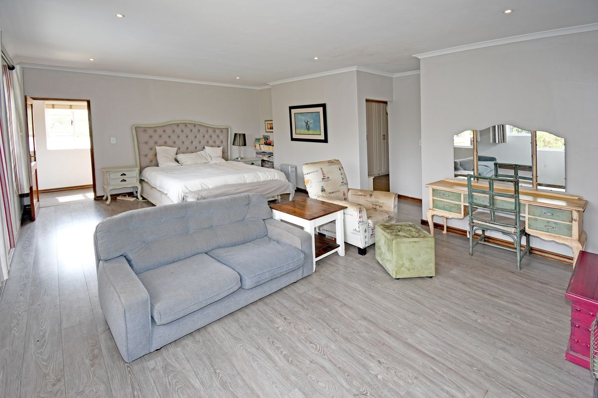Spacious bedroom featuring light-toned wood-look flooring, recessed ceiling lighting, and an open-plan layout with access to an adjoining room.