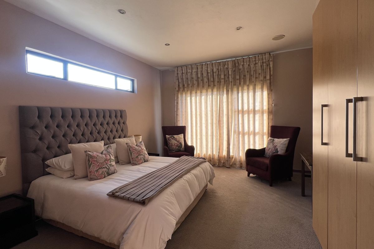 Spacious bedroom featuring neutral carpeting, built-in cupboards, recessed downlighting, and a clerestory window providing natural light.
